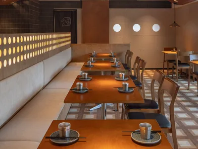 Modern restaurant interior featuring wooden tables, metallic accents, and ceramic elements.