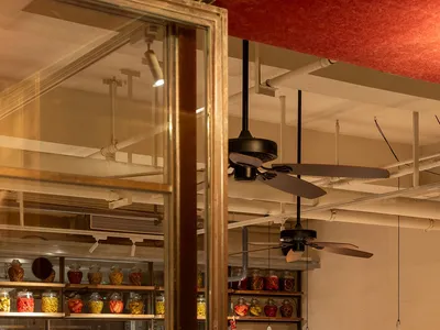 Industrial-themed restaurant interior with wooden furniture and shelves displaying jars and baskets.