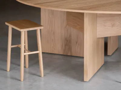 A minimalist dining room with a wooden table and stool, focusing on natural wood textures and a serene aesthetic.