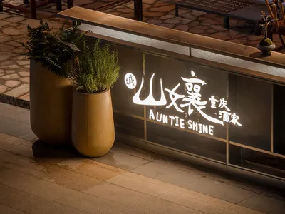 Modern restaurant exterior with metal and concrete surfaces and potted plants.