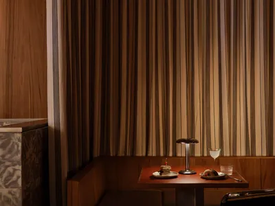 A modern restaurant interior featuring a wooden table with food and drinks.