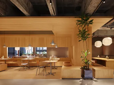 A modern restaurant interior with wooden walls, tables, and seating areas, featuring plants and hanging lantern-style lights.