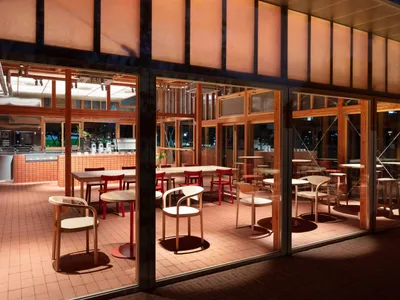 Modern restaurant interior with wooden tables and chairs, glass walls, and exposed beams