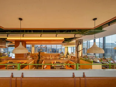 A modern cafe bar interior with wooden booths, metal pendant lights, and glass walls.