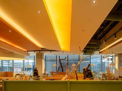 Modern restaurant interior with concrete walls, glass windows, and wooden accents.