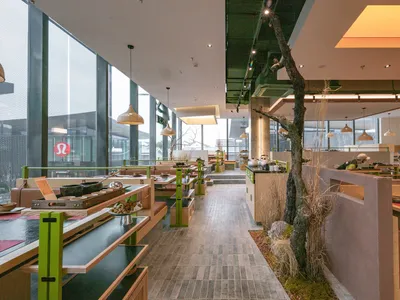 Modern restaurant interior with industrial design elements, featuring wooden furniture and concrete columns.
