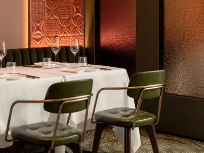 A meticulously designed restaurant interior with a minimalist aesthetic, featuring textured wallcoverings and a warm, invitin