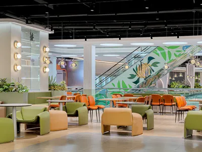 Modern restaurant with orange leather chairs and glass tables.