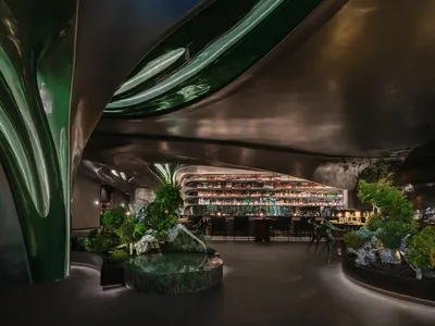 Modern restaurant bar with metal-cladding walls, green lighting, and green plants