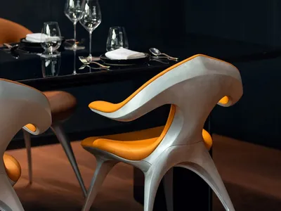 A sleek, modern dining area featuring metallic chairs with orange seats and a dark table, complemented by elegant glassware a