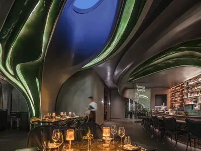 Luxurious modern restaurant interior with metallic ceiling and lighting features.