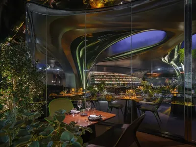An interior design of a modern restaurant featuring metallic glass walls and a contemporary design aesthetic.