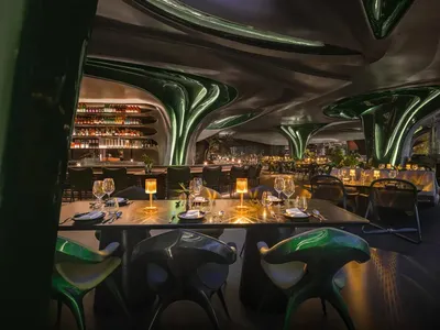 Modern restaurant interior with metallic accents and a skylight.