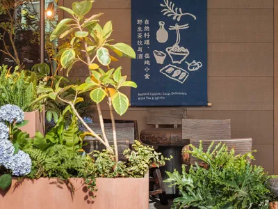 Outdoor seating area with wooden furniture and plants for a cafe.