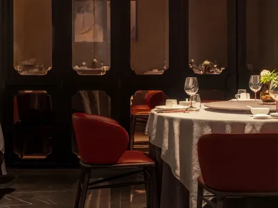 Modern restaurant interior with red leather chairs and round dining table.