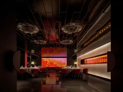A modern restaurant interior featuring metallic and plastic materials with a large digital display of a scenic landscape.