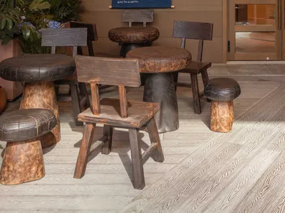 Industrial-style restaurant exterior with wooden tables, chairs, and stools.