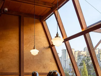 Industrial-style restaurant interior featuring wooden tables, metal chairs, and glass windows.