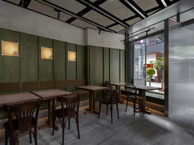 Industrial restaurant interior with green wooden walls, wooden tables, and chairs.