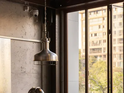 Industrial-style restaurant interior with metal pendant light, wood seating, and metal shelves.
