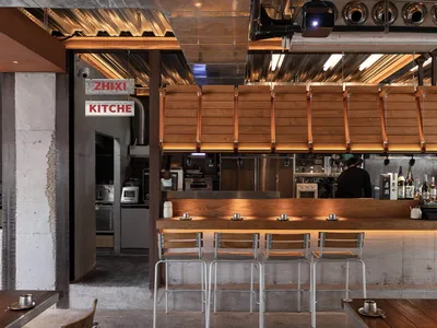 Industrial-style restaurant bar counter with concrete, wooden, and metallic materials