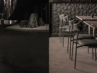 Modern restaurant interior with black walls, steel elements, and concrete floor.