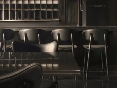 Industrial-themed restaurant interior with metallic counter, leather seating, and glass partitions.