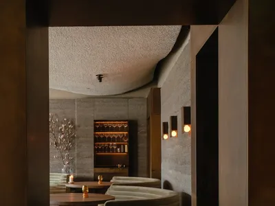 現代工業風餐廳酒吧，裸露混凝土牆面、弧形座椅與溫暖燈光。