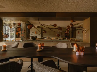 A modern restaurant interior with wooden furniture, glass fixtures, and a warm, inviting atmosphere