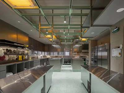 Modern industrial kitchen with marble countertops, industrial-style lighting, and stainless steel appliances.