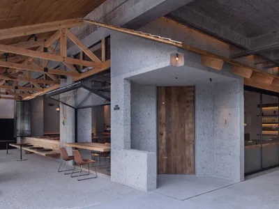 A modern restaurant with exposed concrete walls and wooden accents.