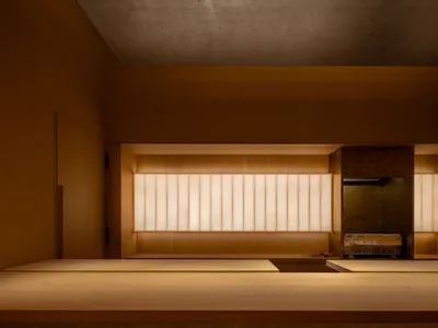 A modern restaurant interior with wooden tables and warm lighting.