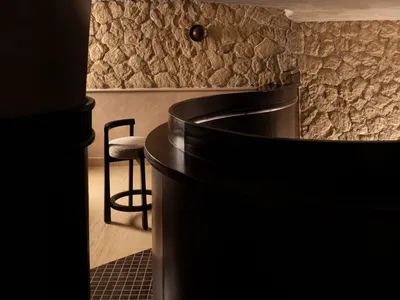 Interior of a modern restaurant featuring a stone wall and a curved metal counter.