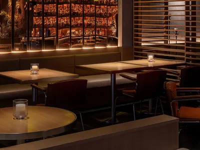 A dimly lit, industrial-style restaurant interior featuring wood accents and a well-lit back bar.