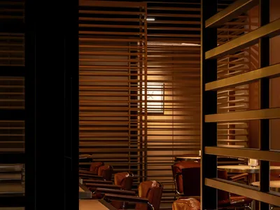 A row of brown leather restaurant seating with wood tables and metal legs.