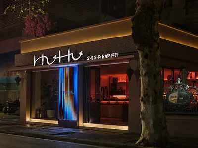 A modern bar storefront with illuminated lights and concrete facade
