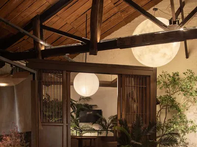 Industrial-style restaurant interior with concrete and wooden elements and large spherical lights.