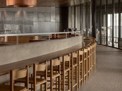 A minimalist restaurant interior featuring concrete, wood, and metal materials.