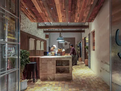 A restaurant bar featuring industrial design elements with timber accents and exposed ceiling beams.