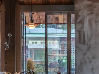 A stylish dining area with wooden furniture and large windows, offering a cozy and contemporary atmosphere.
