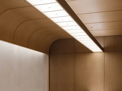 A minimalist restaurant interior with long wooden tables, chairs, and a sleek design.