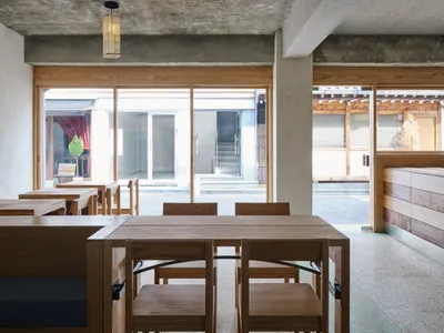 A modern restaurant interior with wooden furniture and concrete ceiling