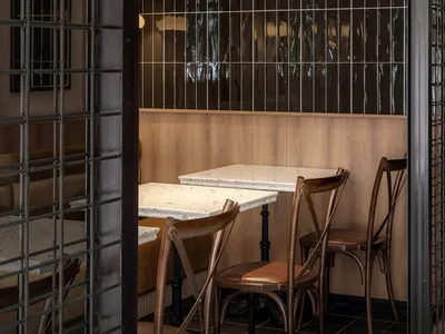 Modern restaurant interior with black tiles and wooden furniture.