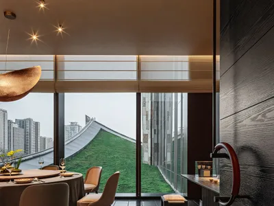 A modern restaurant interior with black lighting, metallic accents, and a rooftop view of the cityscape.