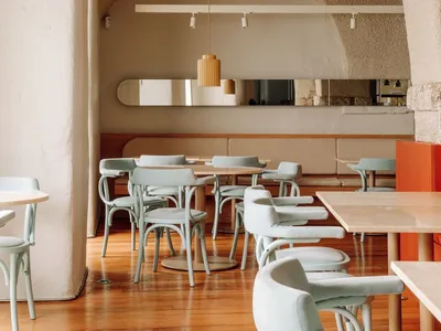 An empty minimalist restaurant interior with concrete walls and wooden floor.