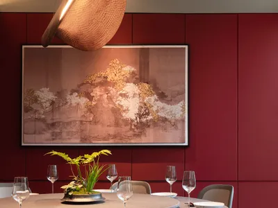 Modern dining room interior with glass and metal features, including a round table, chairs, and hanging light fixture.