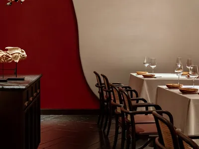 A modern restaurant interior with red velvet walls and white furniture.