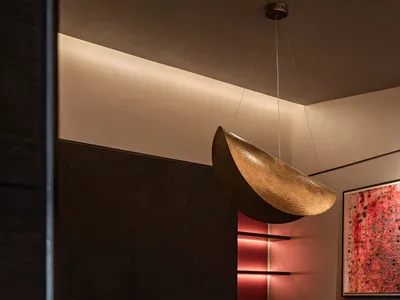 A modern restaurant interior with metallic pendant lighting and red lighting accents.