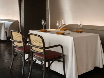 簡約餐廳桌台佈置，搭配布面桌巾、木製餐椅與高腳酒杯。