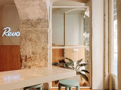 A modern restaurant featuring concrete and wooden materials with a glass barrier and neon signage.